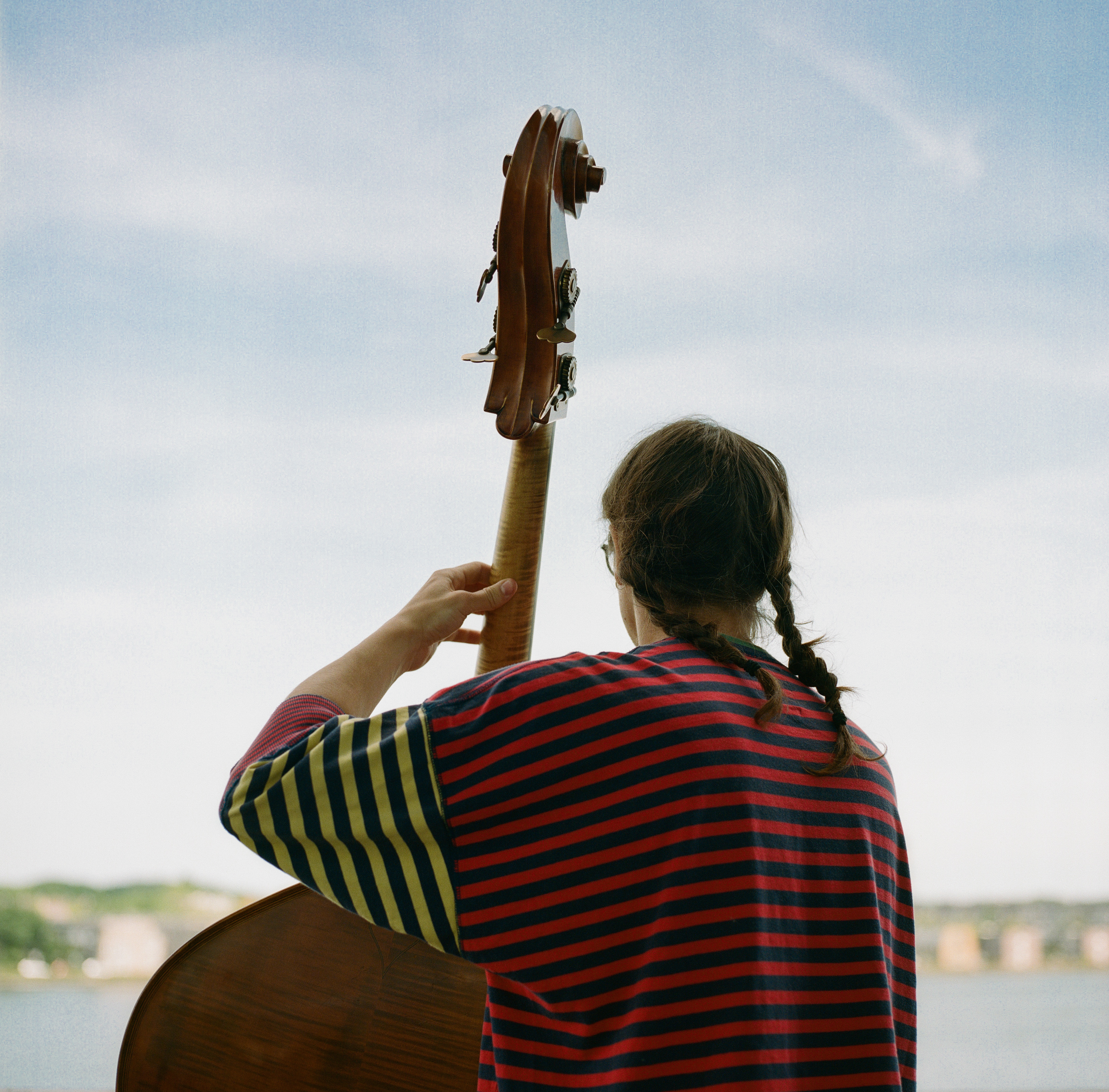 a picture of David from the back, playing the bass wearing braids and a striped shirt